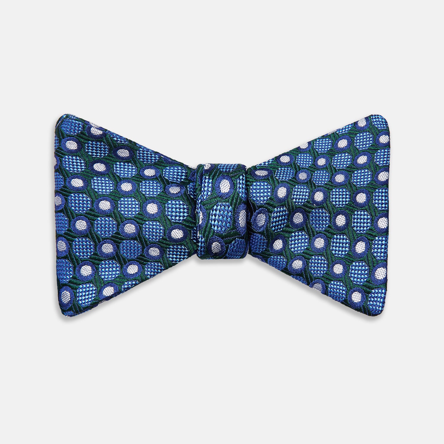View 1 of product The Turnbull & Asser Forest Green and Blue Circle and Spot Silk Bow Tie showcases a blue, green, and white dotted pattern, set against a plain white background.