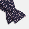 View 3 of product The Navy and Pink Paint Spot Silk Bow Tie by Turnbull & Asser features small, light pink oval dots evenly spaced on navy blue silk, creating a stylish formal accessory.