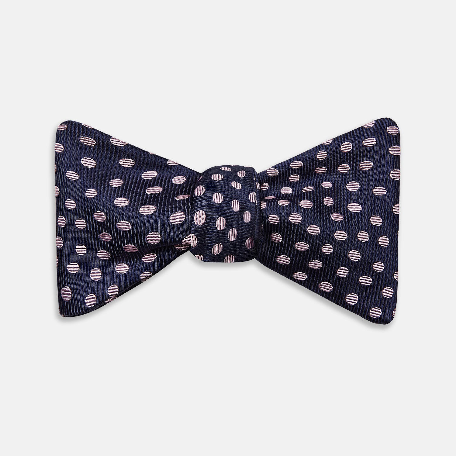 View 1 of product The Navy and Pink Paint Spot Silk Bow Tie by Turnbull & Asser features small, light pink oval dots evenly spaced on navy blue silk, creating a stylish formal accessory.