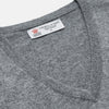 View 2 of product The Turnbull & Asser Flannel Grey V-Neck Cashmere Jumper, shown laid flat on a white background, features long sleeves and ribbed cuffs, hem, and neckline for a classic look with no visible patterns or embellishments.