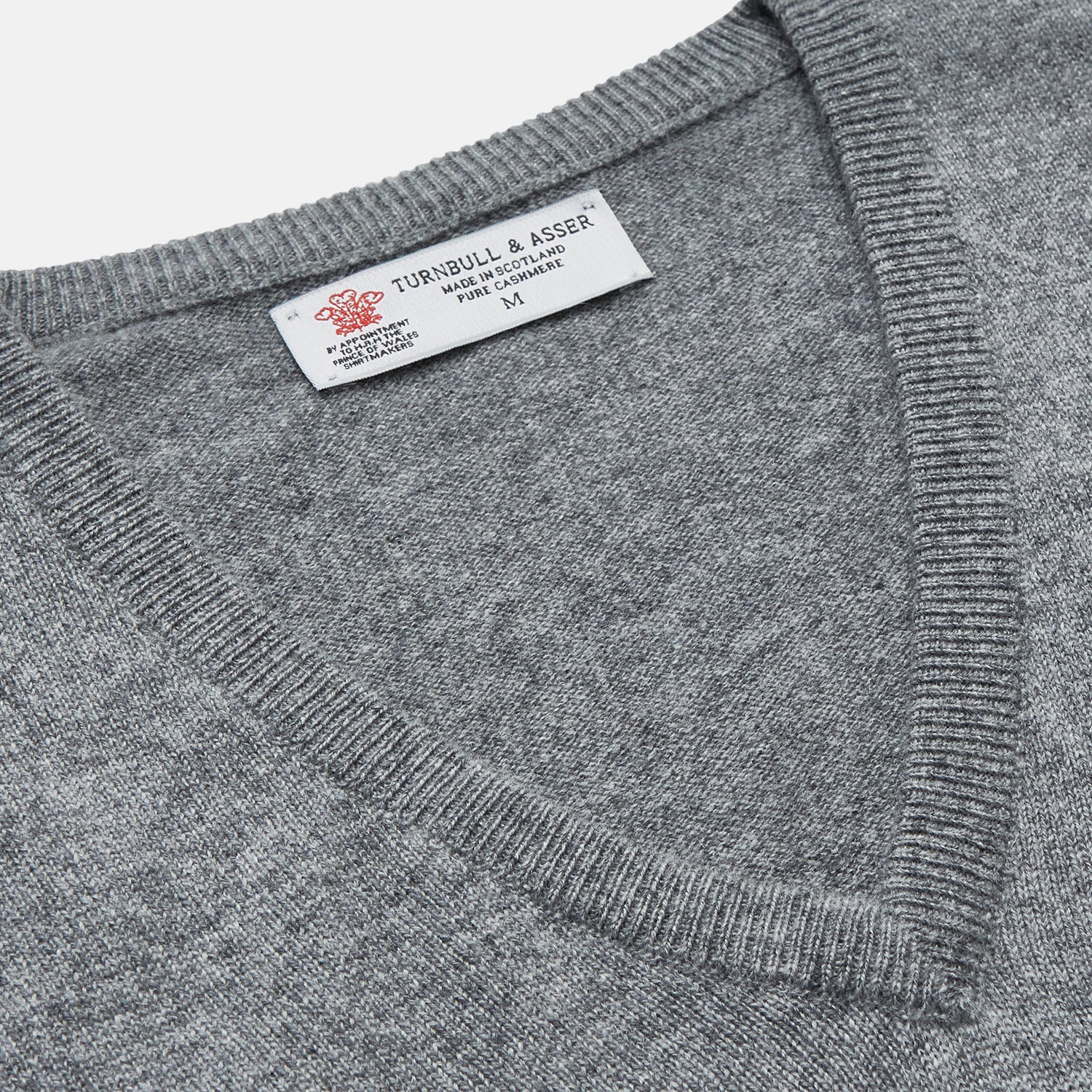 View 2 of product The Turnbull & Asser Flannel Grey V-Neck Cashmere Jumper, shown laid flat on a white background, features long sleeves and ribbed cuffs, hem, and neckline for a classic look with no visible patterns or embellishments.