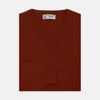View 1 of product The Turnbull & Asser Harissa V-Neck Cashmere Jumper is shown folded in deep red with ribbed cuffs and a visible collar label, set against a white background.