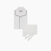 View 1 of product Turnbull & Asser's White Sea Island Cotton Pyjama Set, featuring a folded white men's top with dark piping and a matching face mask, is showcased on a plain white background.