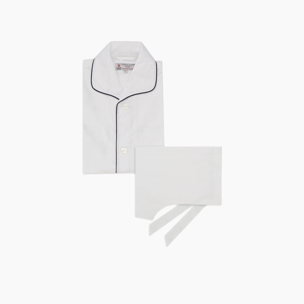 Turnbull & Asser's White Sea Island Cotton Pyjama Set, featuring a folded white men's top with dark piping and a matching face mask, is showcased on a plain white background.