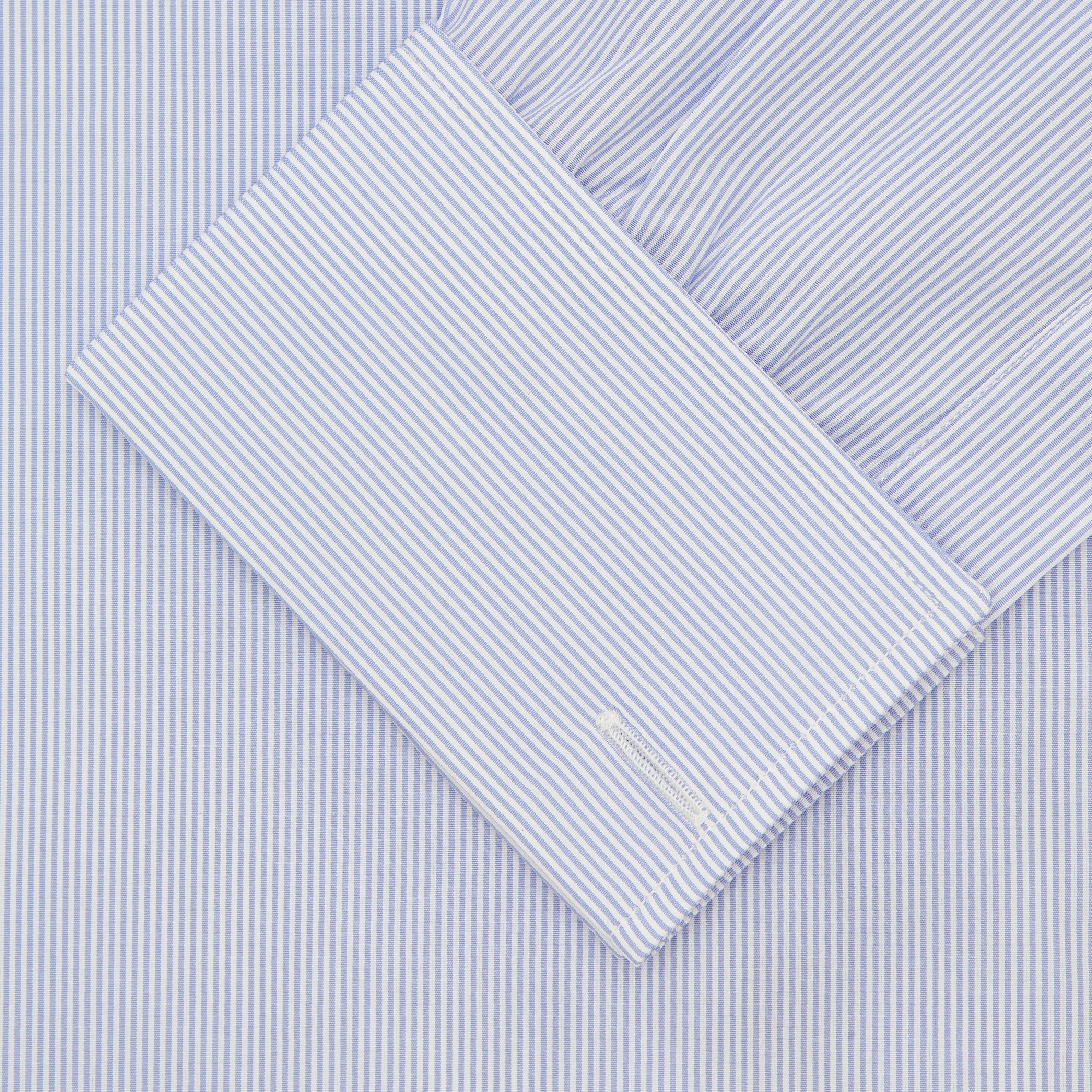 View 2 of product The Turnbull & Asser Blue and White Sea Island Quality Cotton Fine Bengal Stripe Shirt features a Regent collar, double cuffs, white buttons, and a front pocket. Displayed neatly folded against a plain white background.