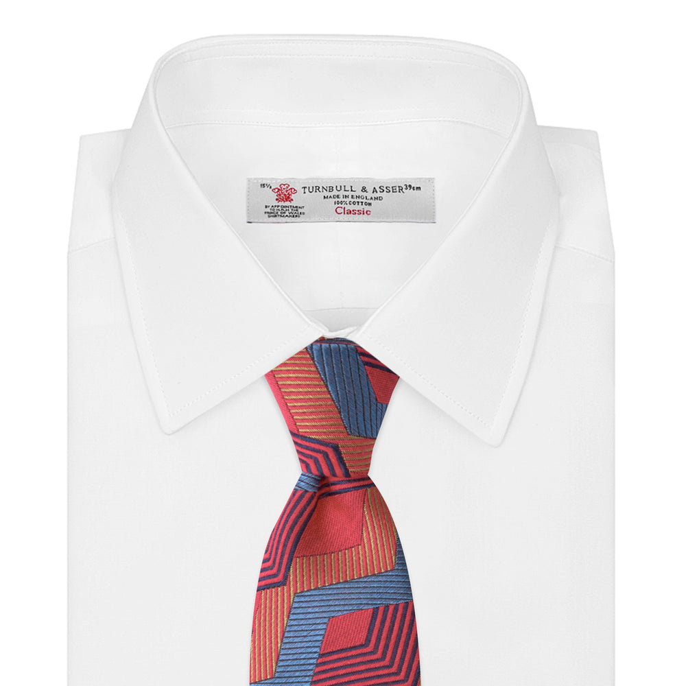 The Turnbull & Asser Red and Blue Zig Zag Silk Tie is a limited-run silk tie featuring interlocking geometric zigzag shapes and diagonal stripes in red, blue, gold, and navy.