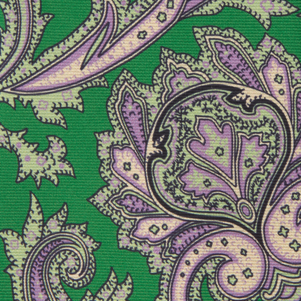 The Turnbull & Asser Green and Purple Large Paisley Printed Silk Tie features a light purple and white intricate paisley pattern, rolled up and set against a plain white background for timeless style.
