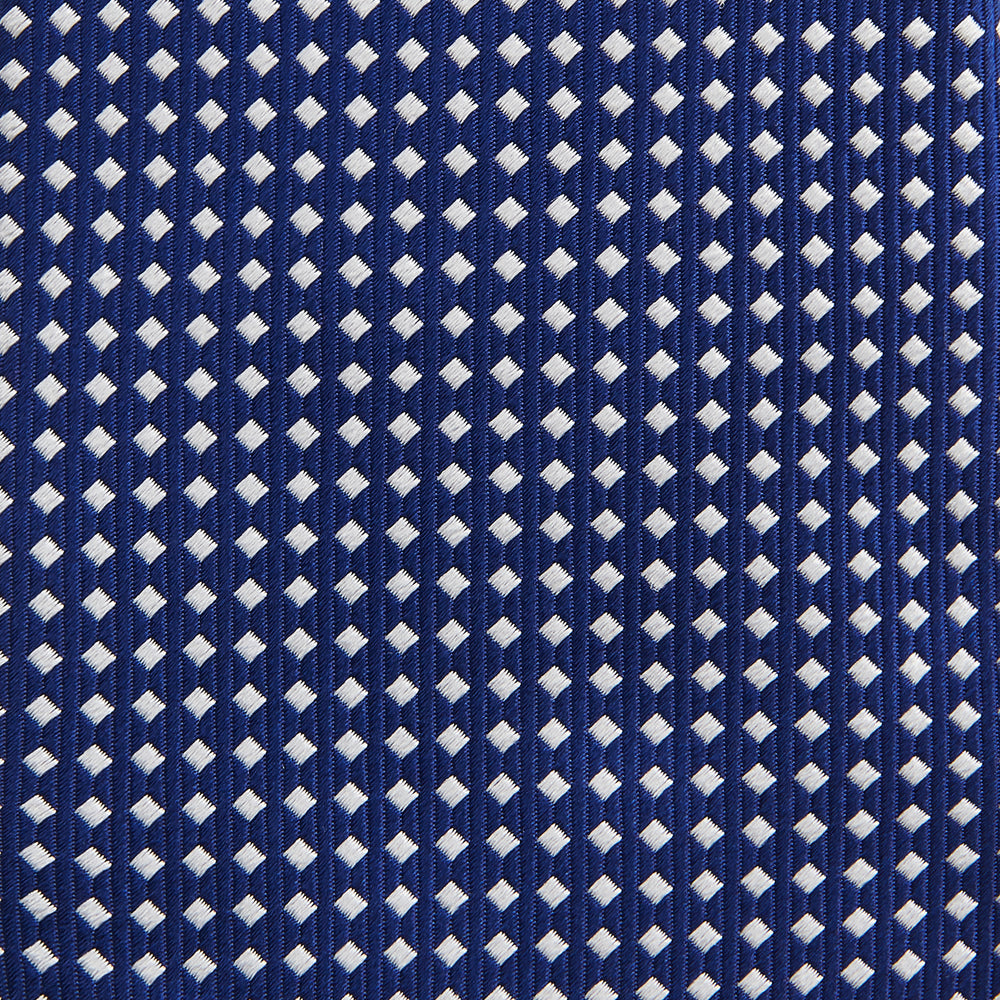 The Turnbull & Asser Slim Diamond Navy and White Silk Tie, featuring a subtle geometric pattern, is rolled up and displayed on a plain white background—ideal for complementing an office shirt.