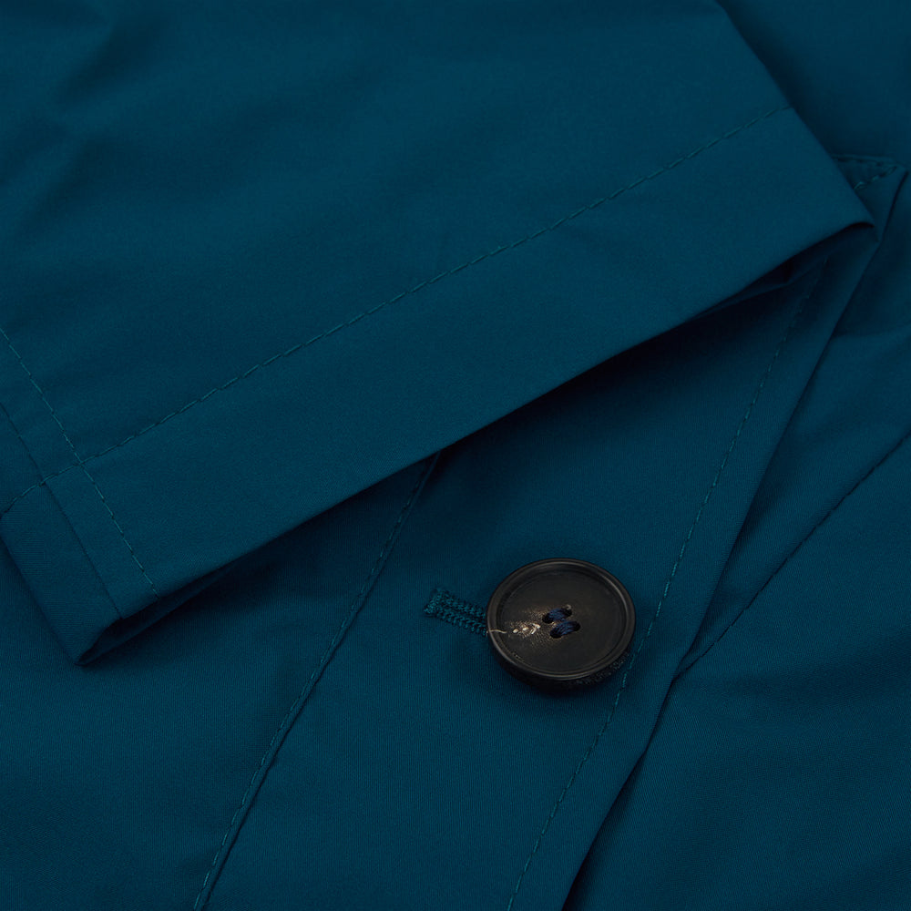 The Turnbull & Asser Blue Pack-Away Rain Mac is a knee-length coat with a classic collar, long sleeves, side buttoned pockets, and a concealed front placket, shown against a plain white background.