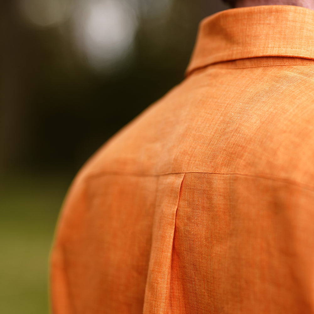 The Turnbull & Asser Orange Weekend Fit Linen Nevis Shirt features a Derby collar, long sleeves with 1-button cuffs, white buttons, and a chest pocket, shown flat against a white background.