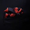 View 3 of product The Navy and Cherry Red Tiled Floral Silk Pocket Square by Turnbull & Asser features a blue background with red and white geometric floral patterns, a decorative border, and the brand's name in one corner.