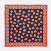 View 1 of product The Navy and Cherry Red Tiled Floral Silk Pocket Square by Turnbull & Asser features a blue background with red and white geometric floral patterns, a decorative border, and the brand's name in one corner.