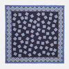 View 1 of product The Navy and Sky Blue Tiled Floral Silk Pocket Square by Turnbull & Asser features a geometric floral pattern in blue and white, a detailed border, and the brand's logo in the bottom right corner.