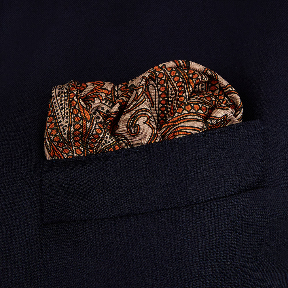 The Orange House Paisley Print Silk Pocket Square by Turnbull & Asser features a brown paisley design on a light brown silk background with a solid brown border and brand's logo printed in one corner.