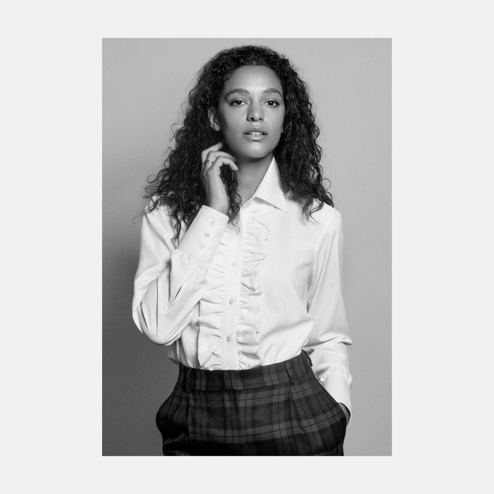 The Turnbull & Asser Turnbull and The Deck Cream Silk Romantic Shirt features long sleeves, a pointed collar, and elegant front ruffles, shown against a plain light gray background.