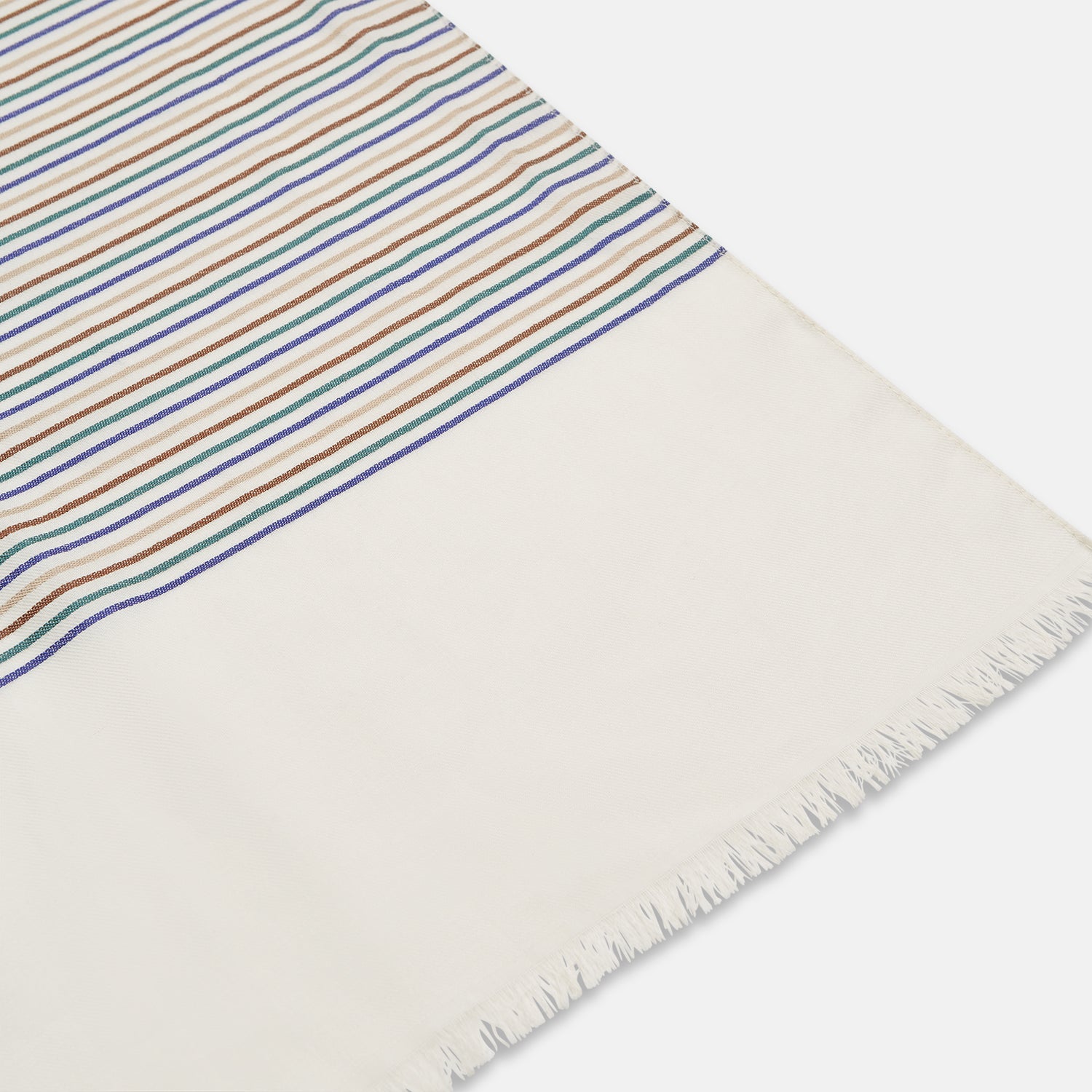 View 3 of product A man wearing a Turnbull & Asser Cream Abstract Stripe Print Lightweight Wool Scarf and a beige shirt stands outside by a tree, surrounded by greenery, gazing thoughtfully to the side.