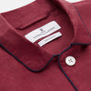 View 5 of product The Turnbull & Asser Burgundy Linen Modern Pyjama Set features a button-up, collared long-sleeve top with black piping and three pockets, plus matching pants with an elastic waistband.