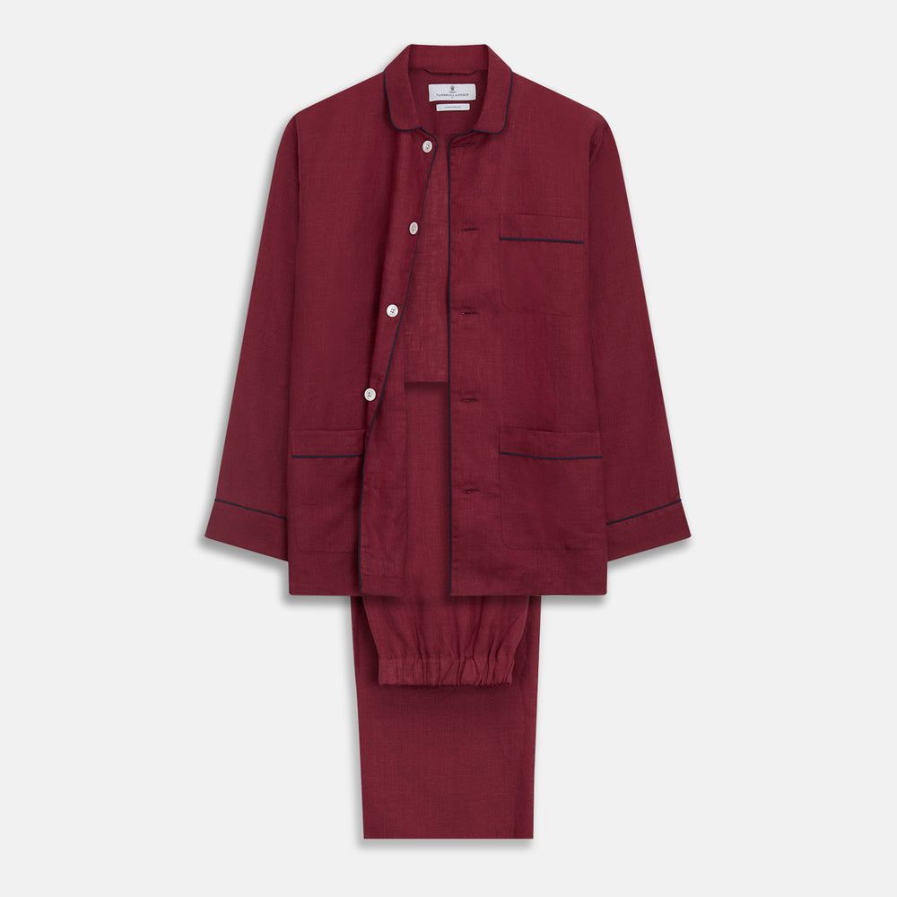 The Turnbull & Asser Burgundy Linen Modern Pyjama Set features a button-up, collared long-sleeve top with black piping and three pockets, plus matching pants with an elastic waistband.