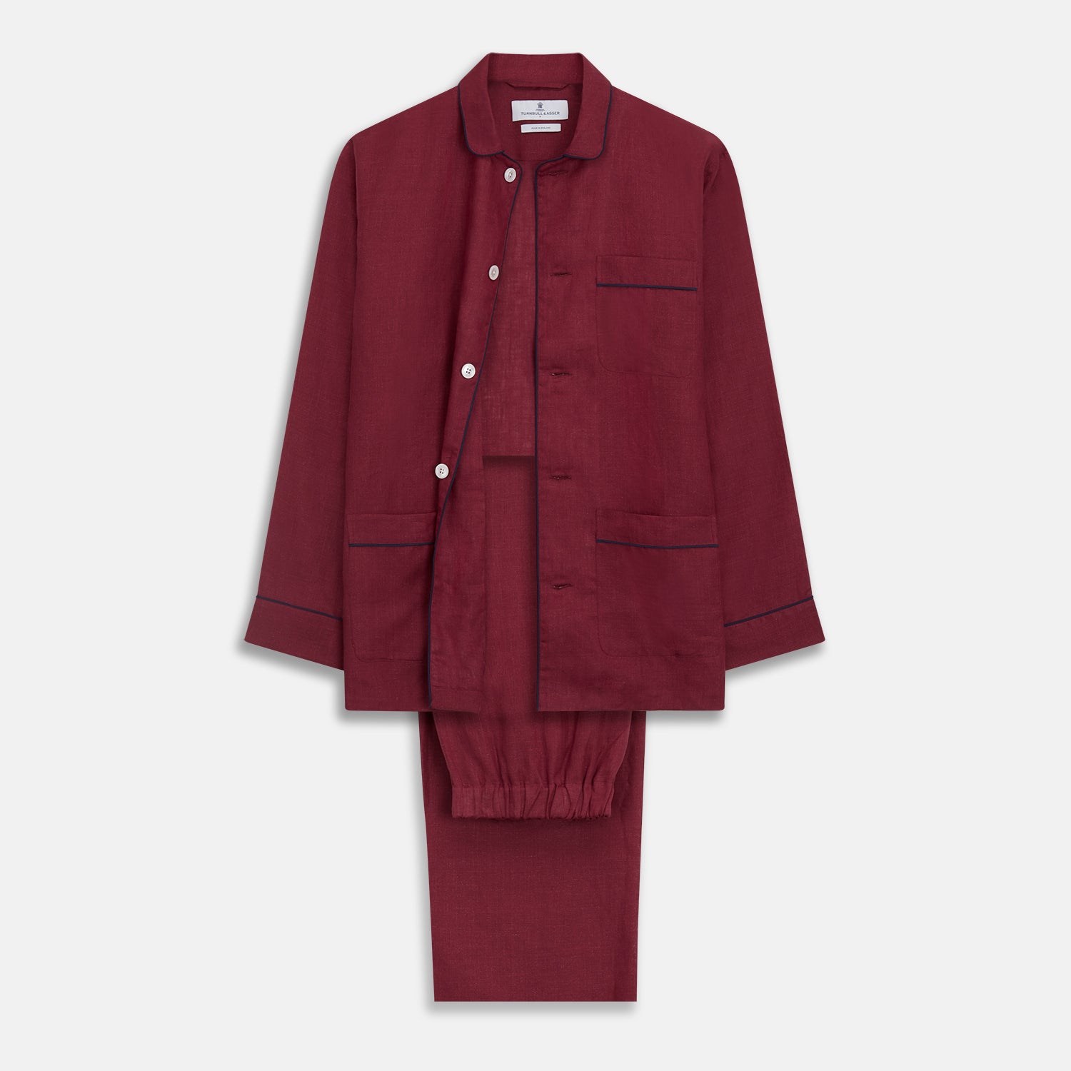 View 1 of product The Turnbull & Asser Burgundy Linen Modern Pyjama Set features a button-up, collared long-sleeve top with black piping and three pockets, plus matching pants with an elastic waistband.