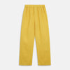 View 7 of product A barefoot person stands against a plain background, wearing the Turnbull & Asser Ochre Linen Modern Pyjama Set with black piping on the collar, cuffs, and pockets. The button-down top completes the look as they gaze to the side.