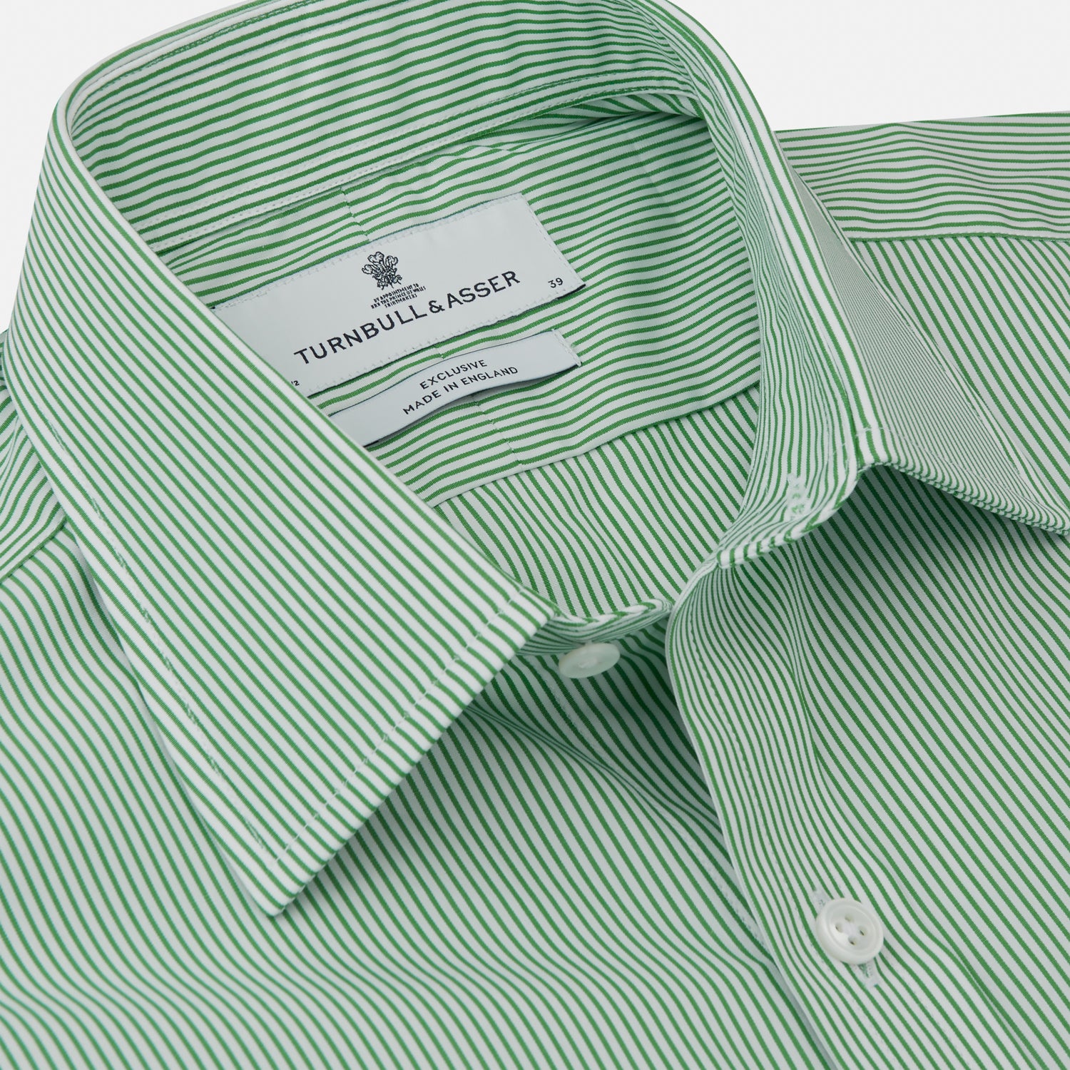 View 5 of product A man stands against a plain background, wearing a Turnbull & Asser Green Fine Stripe Regular Fit Shirt with a T&A collar, paired with a yellow tie, dark trousers, and black shoes. He looks slightly left with his hands at his sides.
