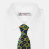 View 2 of product The Yellow Medallion Printed Silk Tie by Turnbull & Asser features a bold abstract medallion pattern in blue, green, and orange on yellow silk, displayed rolled up against a plain white background.