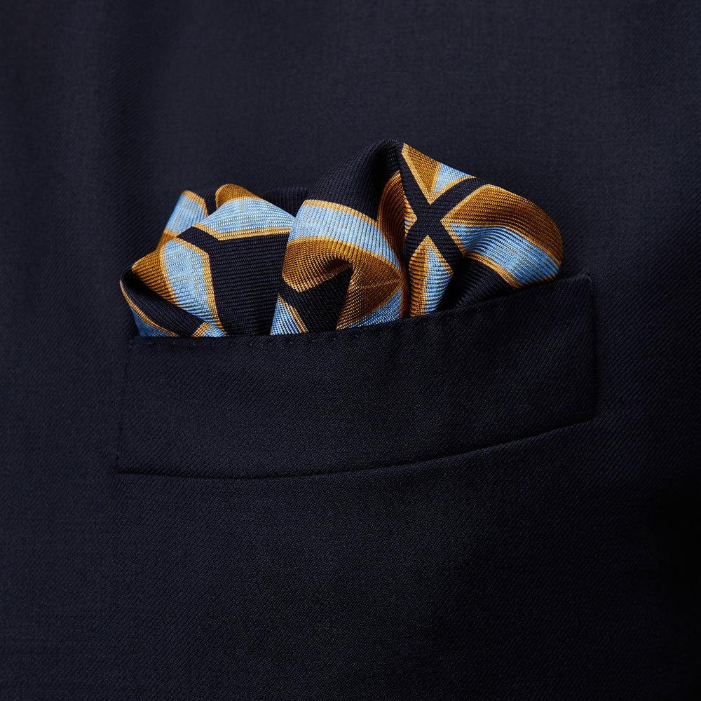 The Turnbull & Asser Navy Multi Crosses Double-Faced Silk Pocket Square features intersecting yellow and white X-shapes on a dark background with a red border, and “TURNBULL & ASSER” plus “PRINTED IN ENGLAND” in two corners.