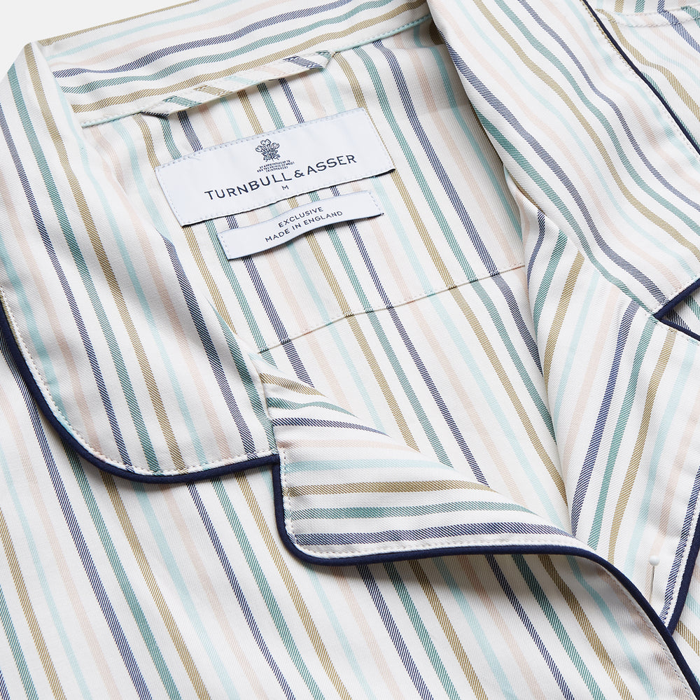Turnbull & Asser’s Green Multi Stripe Harriet Women’s Pyjama Set features premium cotton, a button-up long-sleeve top, drawstring pants, and thin blue, green, and beige stripes on white with black piping for a timeless look.