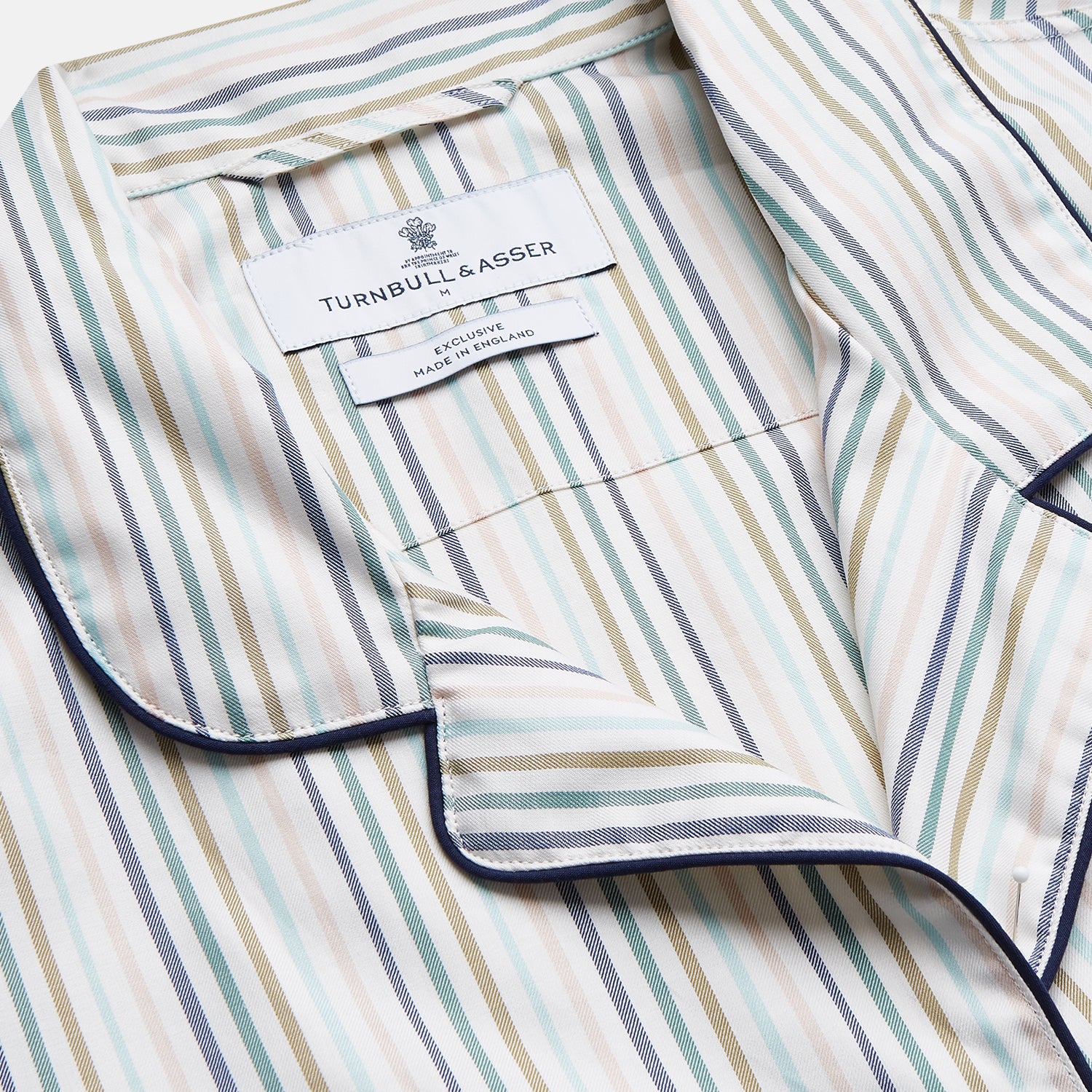 View 3 of product Turnbull & Asser’s Green Multi Stripe Harriet Women’s Pyjama Set features premium cotton, a button-up long-sleeve top, drawstring pants, and thin blue, green, and beige stripes on white with black piping for a timeless look.
