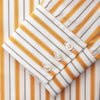View 5 of product A man stands against a tan background wearing a Turnbull & Asser Orange Multi Stripe Regular Fit Shirt with T&A Collar and 3 Button Cuffs, paired with tan dress pants, brown belt, and brown shoes. He faces forward with a neutral expression.