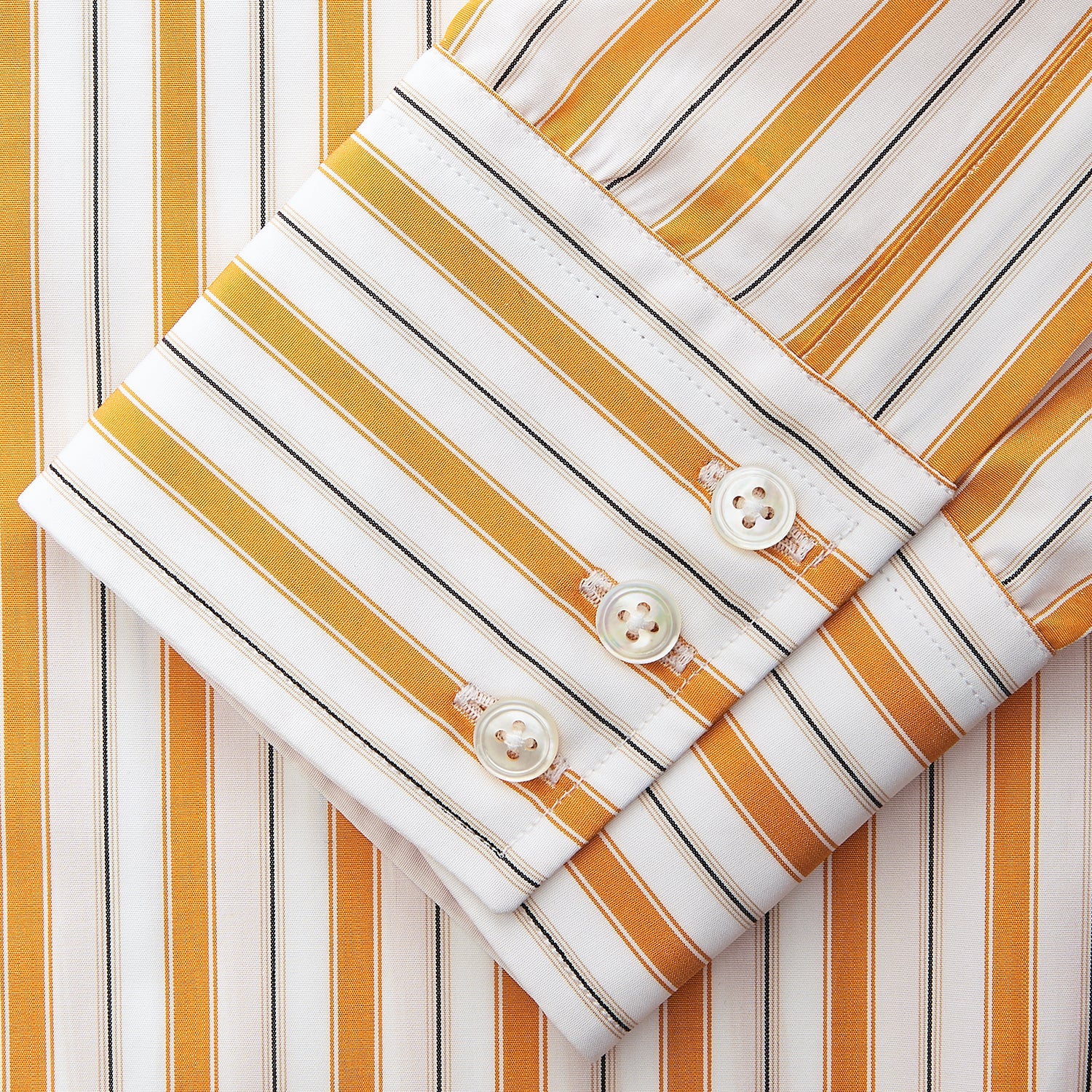 View 5 of product A man stands against a tan background wearing a Turnbull & Asser Orange Multi Stripe Regular Fit Shirt with T&A Collar and 3 Button Cuffs, paired with tan dress pants, brown belt, and brown shoes. He faces forward with a neutral expression.