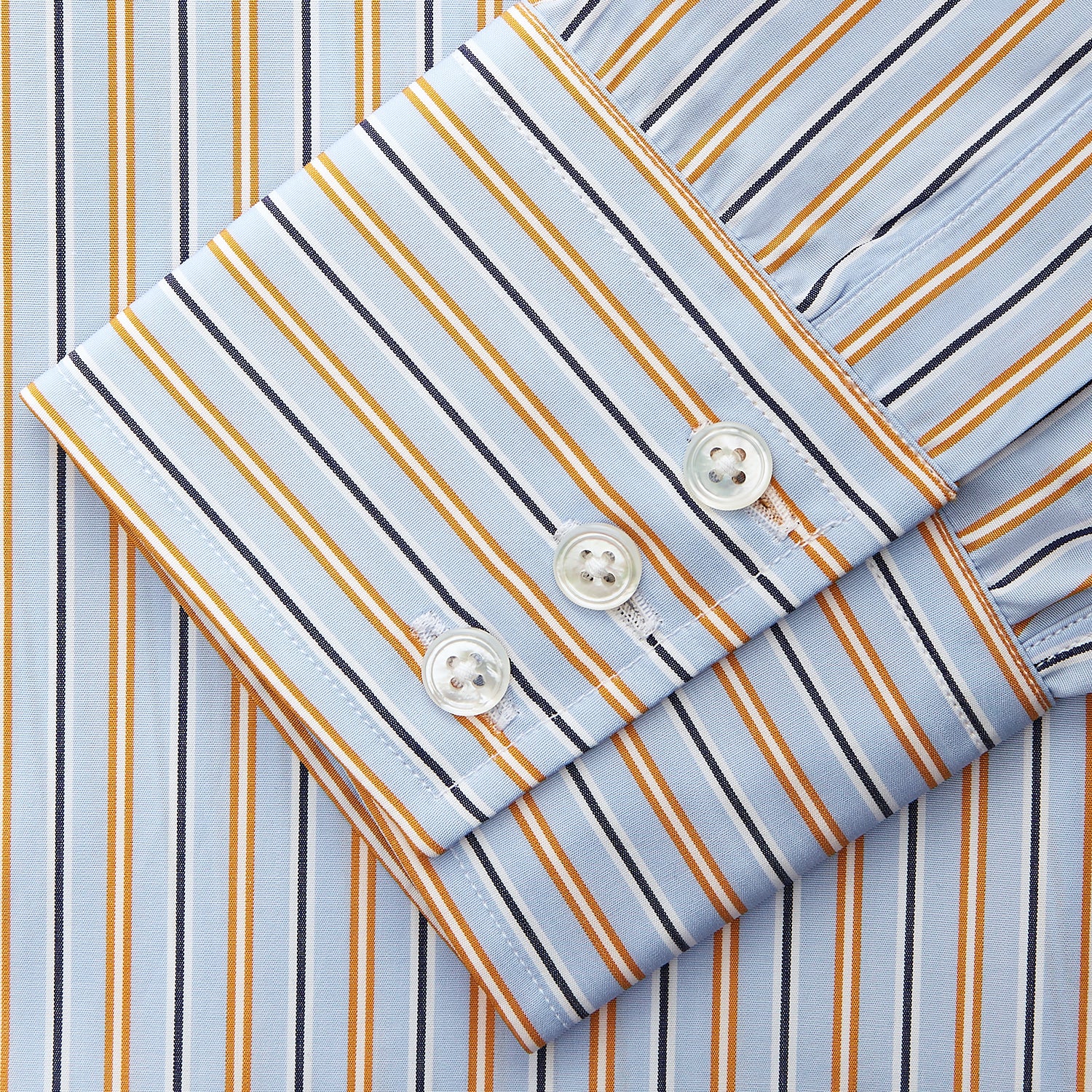 View 4 of product A man stands against a beige background, wearing a Turnbull & Asser Blue, Orange & Navy Multi Stripe Regular Fit Shirt with T&A collar and 3-button cuffs, tucked into tan dress pants with a black belt. He faces forward with a neutral expression.