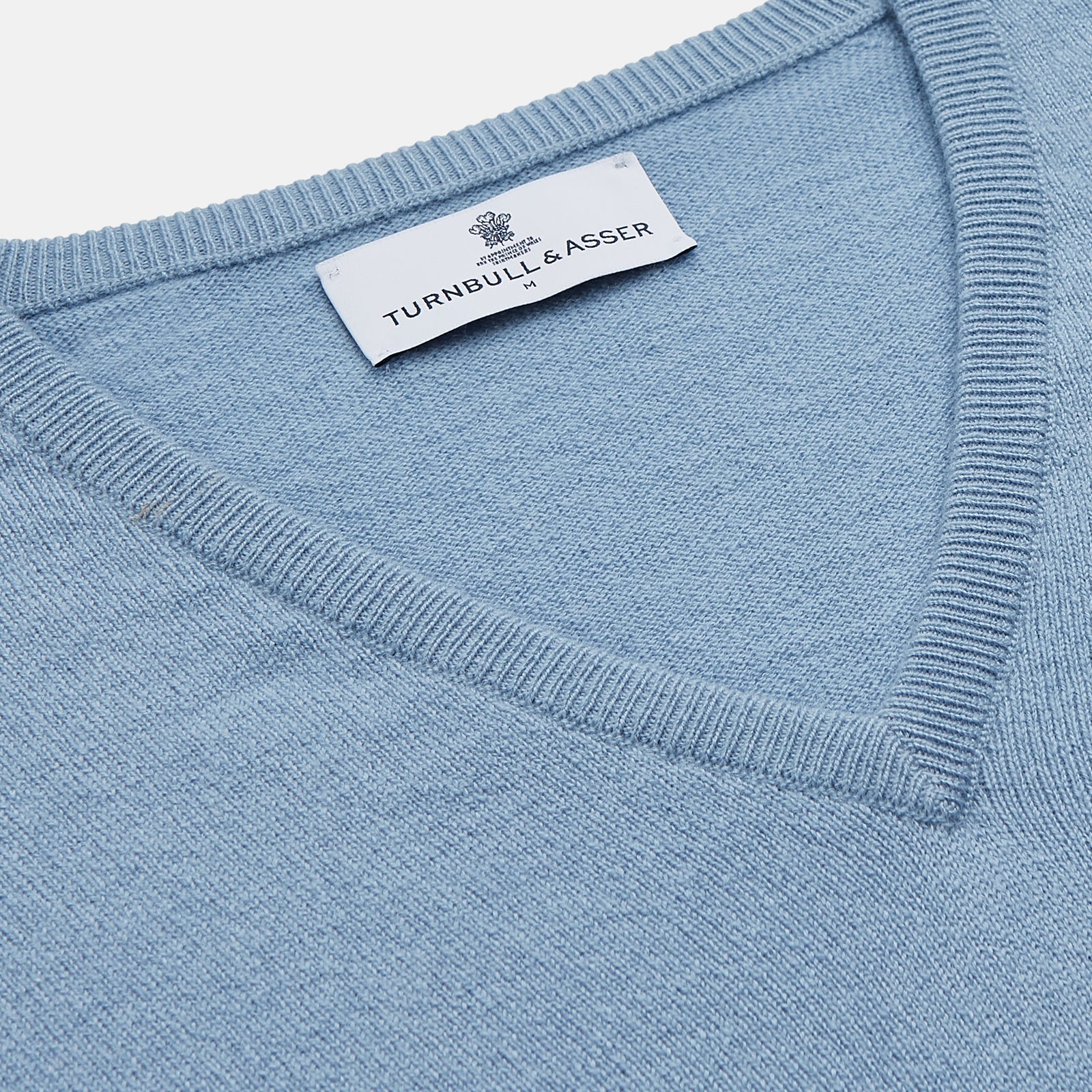 View 2 of product The Turnbull & Asser Pale Blue Cashmere Paden V-Neck Jumper features long sleeves, ribbed cuffs and hem, and is shown laid flat on a white background—an ideal choice for men's style.