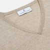 View 2 of product The Turnbull & Asser Beige Cashmere Paden V-Neck Jumper is laid flat on a white background. Knitted in Scotland, this men's staple features ribbed cuffs, hem, and neckline with a soft, smooth texture.