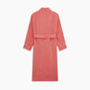 View 5 of product The Pink Linen Arnold Gown by Turnbull & Asser features white piping, long sleeves, a shawl collar, chest pocket, and a wrap-around belt tied at the waist, shown on a white background.