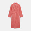 View 1 of product The Pink Linen Arnold Gown by Turnbull & Asser features white piping, long sleeves, a shawl collar, chest pocket, and a wrap-around belt tied at the waist, shown on a white background.