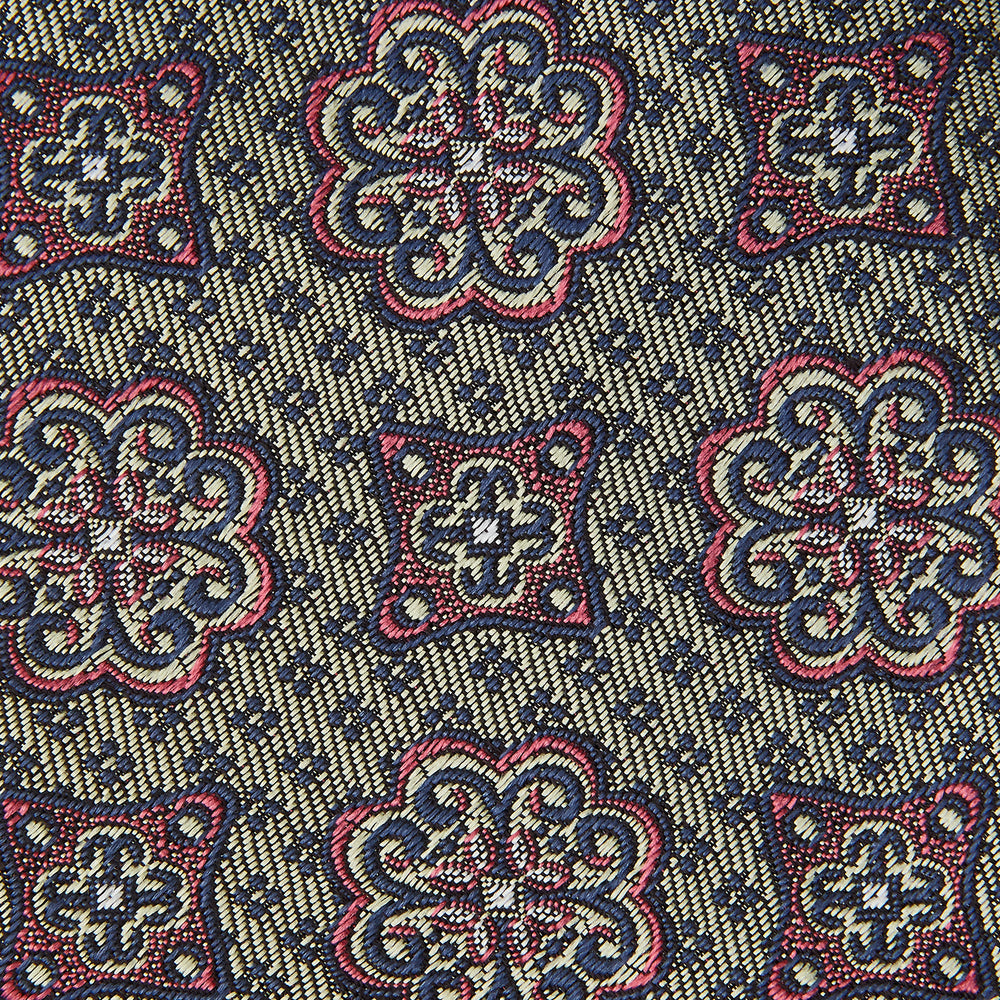 The Green Floral Tile Silk Tie by Turnbull & Asser features a gold background with a repeating green floral pattern in red, navy blue, and cream, showcasing classic style and an evenly distributed silk texture throughout.