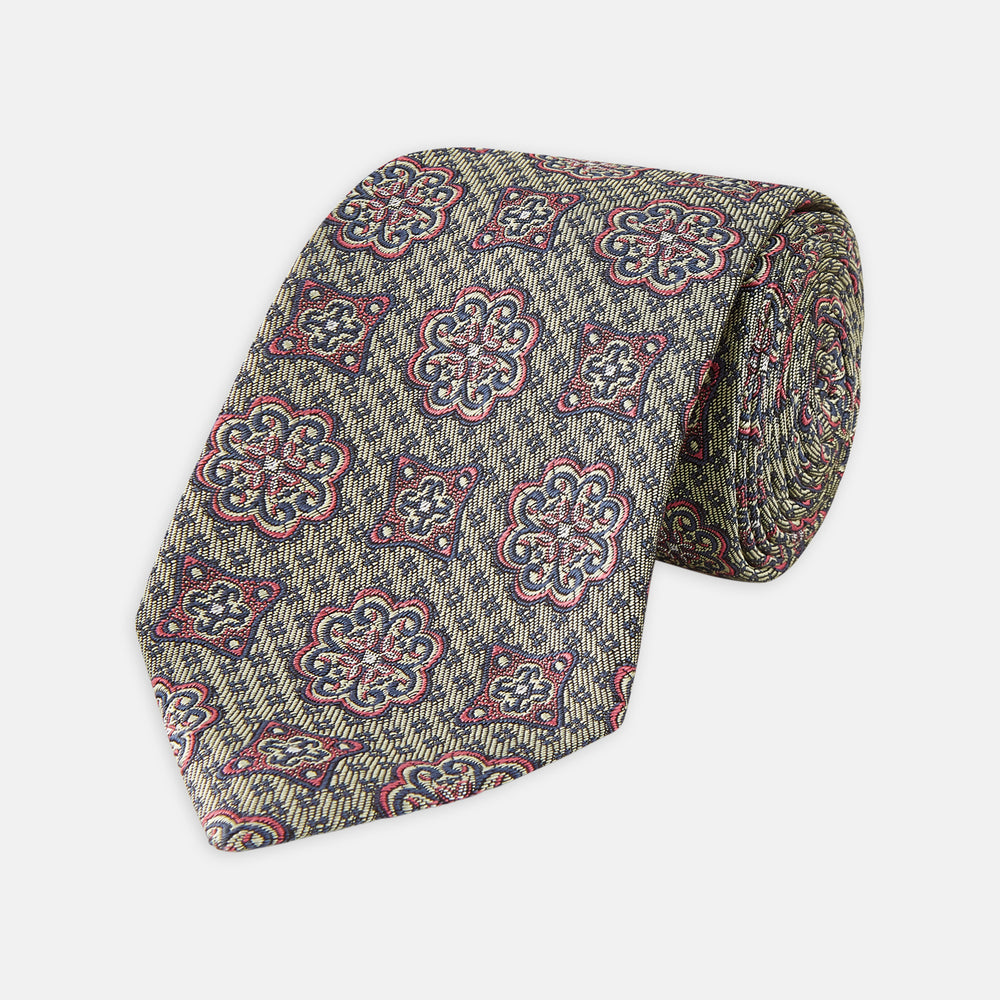 The Green Floral Tile Silk Tie by Turnbull & Asser features a gold background with a repeating green floral pattern in red, navy blue, and cream, showcasing classic style and an evenly distributed silk texture throughout.