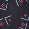 View 2 of product A Turnbull & Asser Navy Graphic Deco Silk Tie, featuring light blue chevrons and red squares on a dark navy background, shown rolled up against a plain white backdrop.