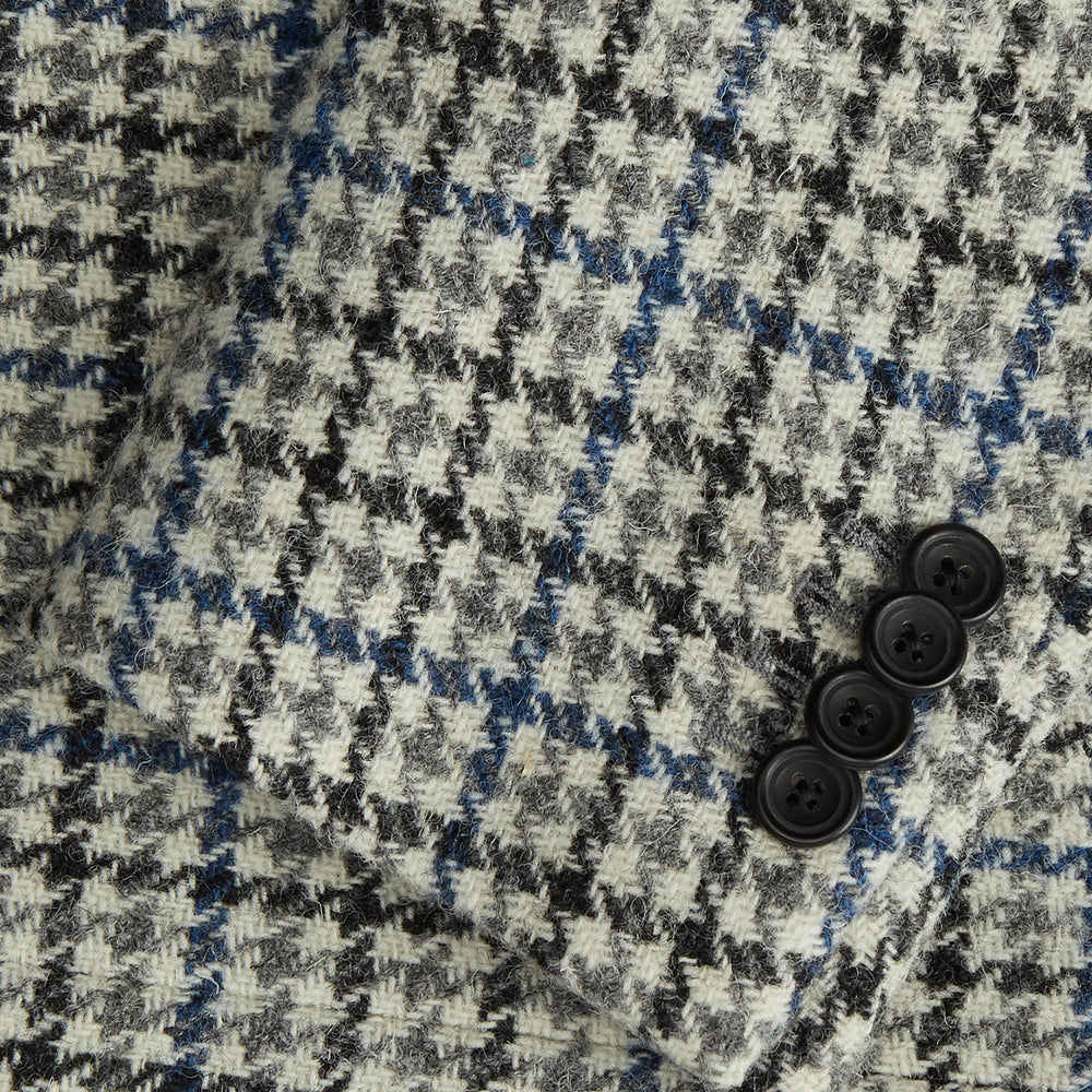 The Grey and Navy Tweed Barrington Blazer by Turnbull & Asser is a single-breasted jacket with notched lapels, two front buttons, flap pockets, and a tailored fit—expertly made in Italy for sophisticated style.