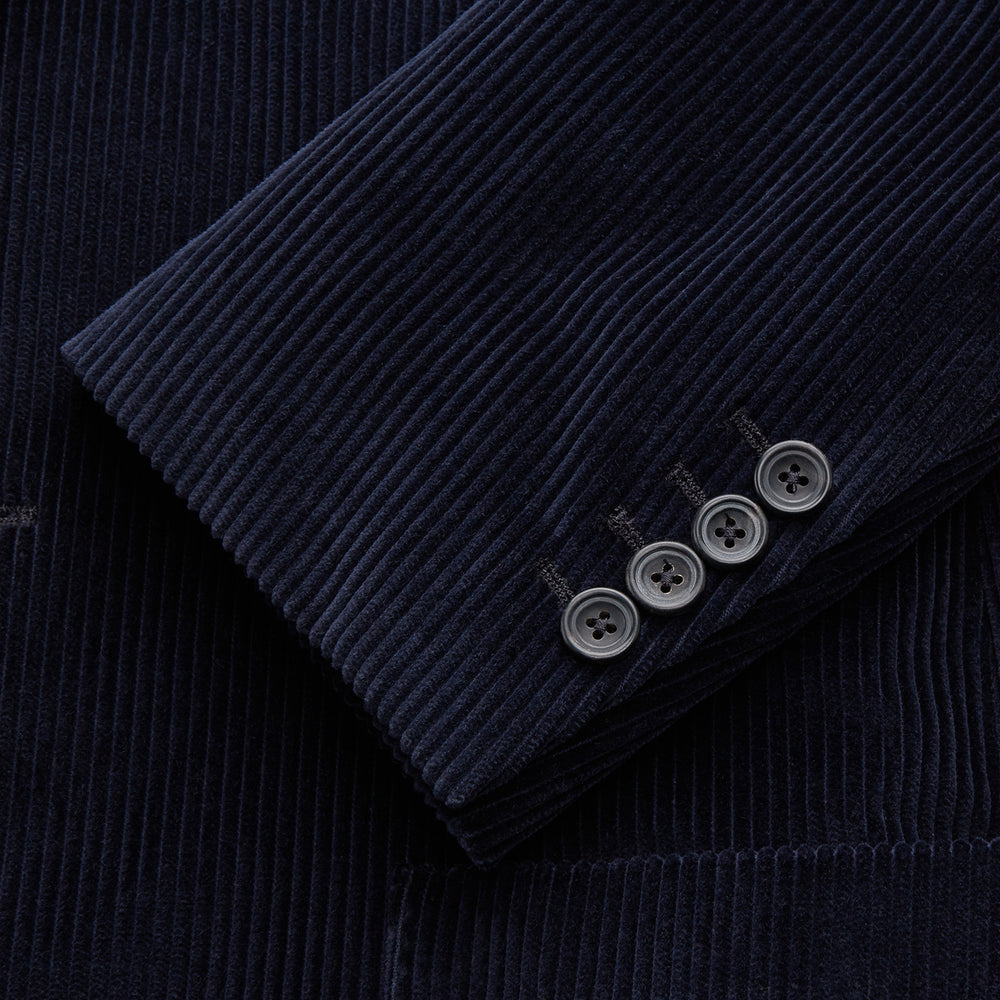 The Turnbull & Asser Navy Cord Bern Blazer, featuring notched lapels, a single button closure, two front pockets, and buttoned cuffs, exemplifies refined Italian tailoring and is shown laid flat on a white background.
