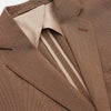 View 3 of product The Brown Virgin Wool Bern Blazer by Turnbull & Asser features notch lapels, two front patch pockets, a chest pocket, buttoned cuffs, and two buttons, shown over a beige collared shirt against a white background.