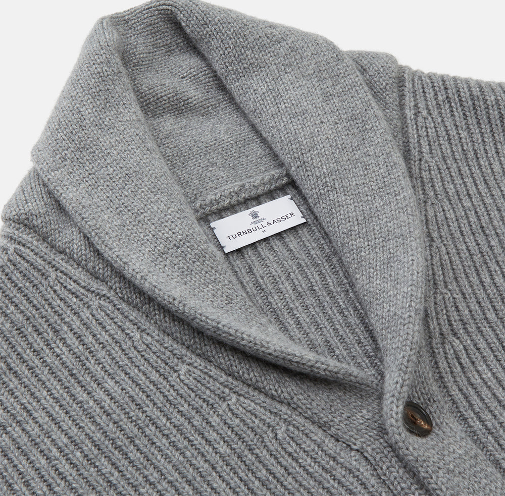 The Turnbull & Asser Grey Ribbed Cashmere Ainsley Cardigan is a luxury 3-ply cashmere knit with a shawl collar, button-up front, and two front pockets, shown laid flat on a white background.
