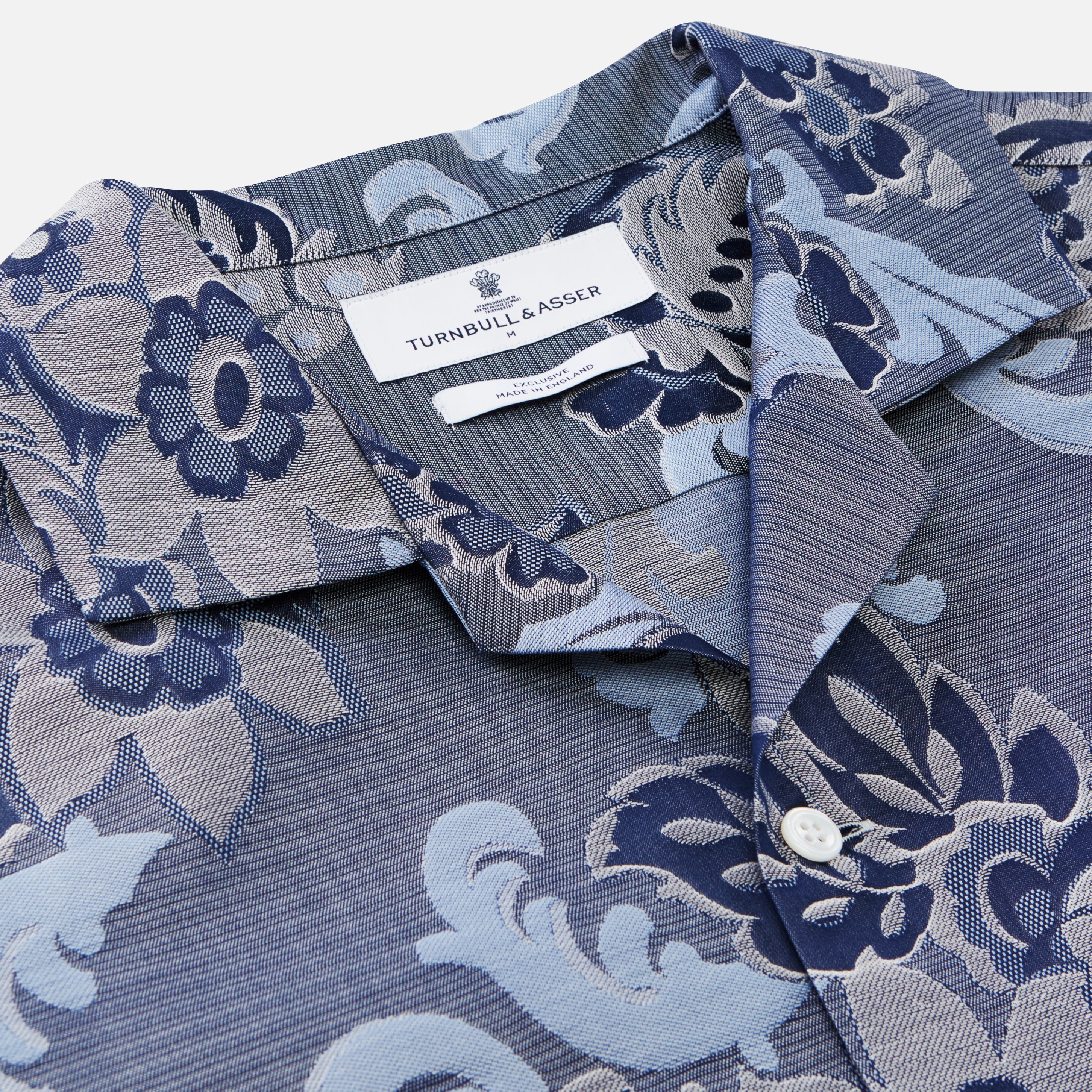 View 2 of product The Blue & White Tapestry Weave Cotton Holiday Fit Shirt by Turnbull & Asser features short sleeves, a revere collar, and a button-up front with a blue and white patterned textured fabric, shown against a plain white background.