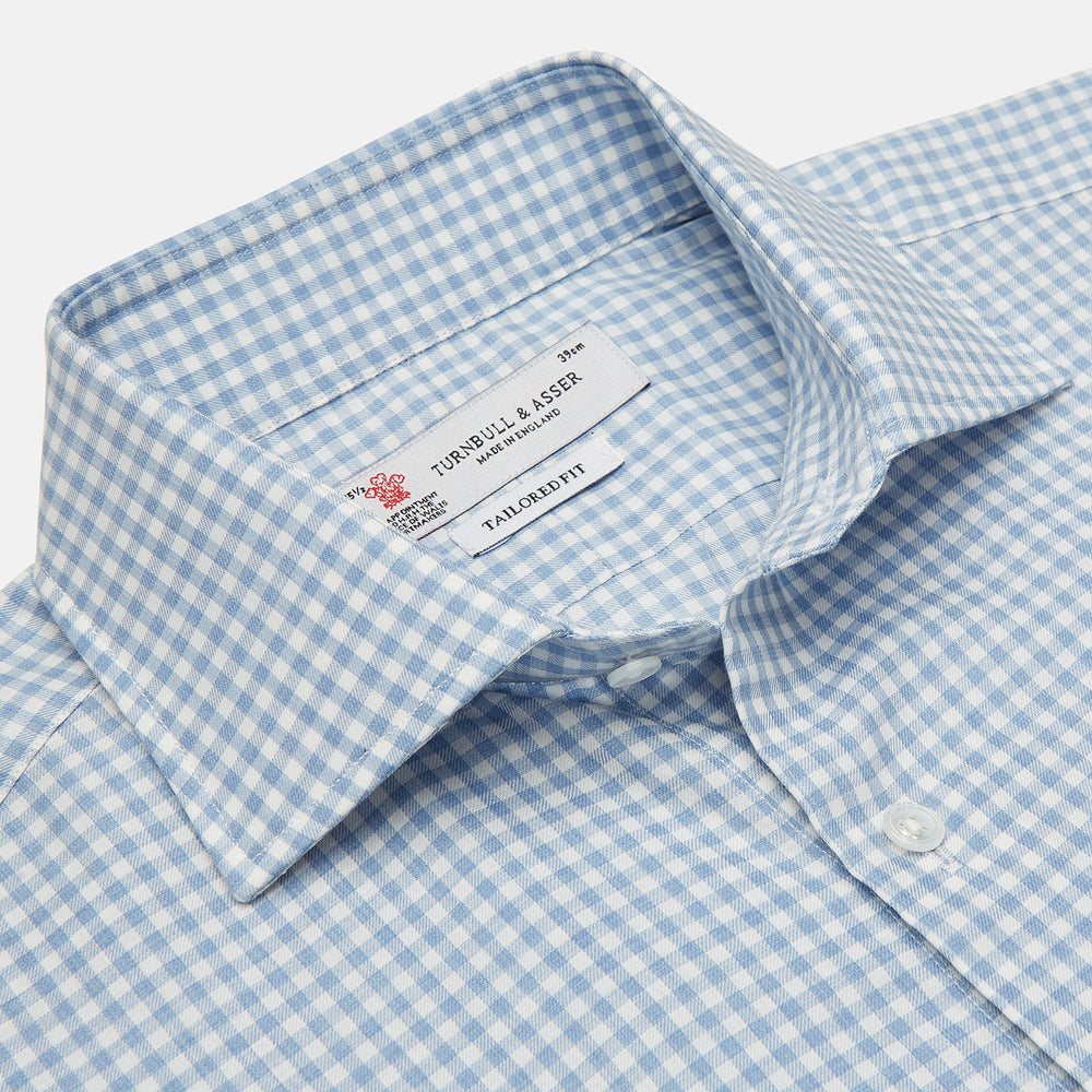 The Turnbull & Asser Tailored Fit Light Blue Gingham Shirt features a Kent collar, 2-button cuffs, and a small blue-and-white checkered pattern, shown on a white background.