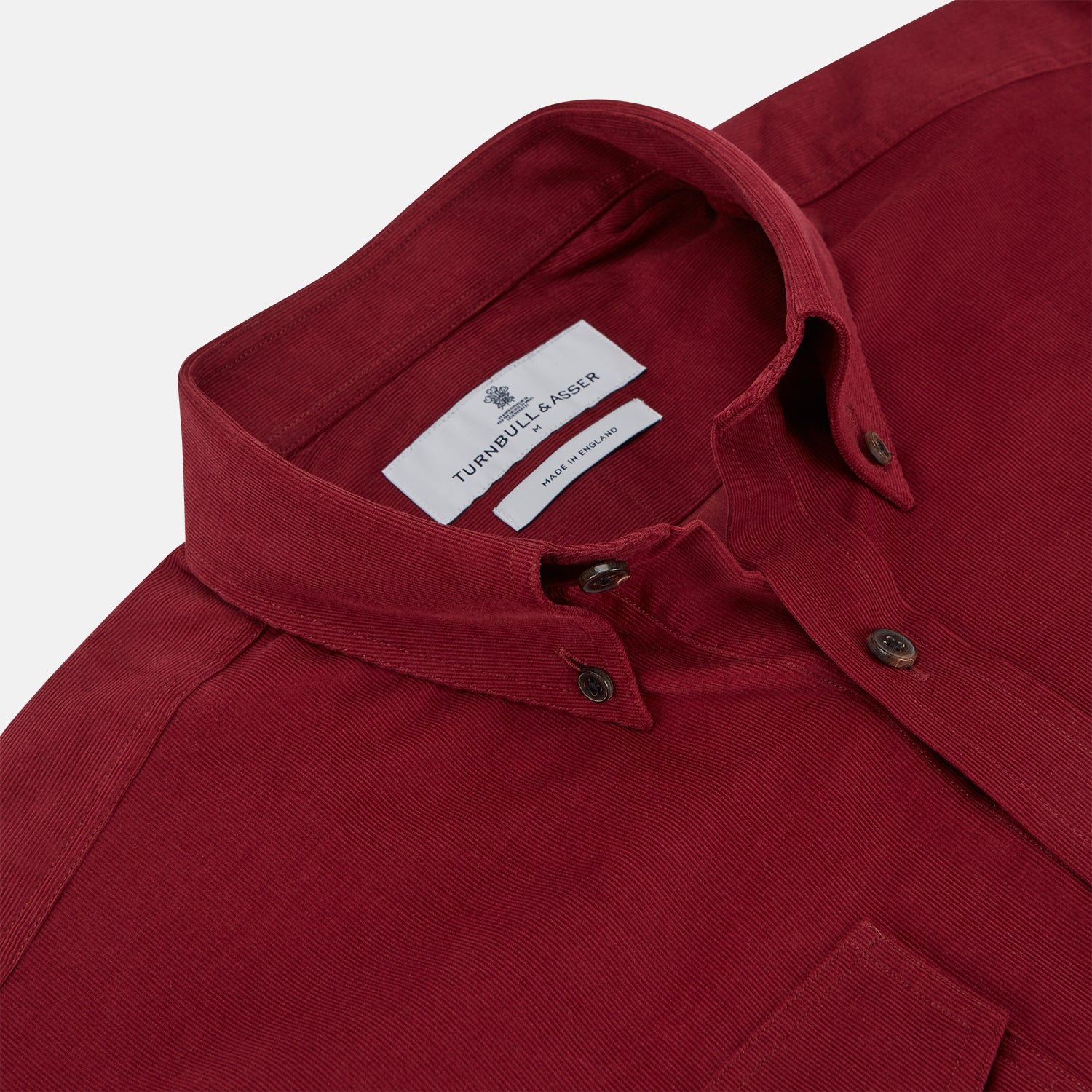 View 2 of product The Turnbull & Asser Burgundy Corduroy Officer Weekend Fit Shirt features a Dorset collar, long sleeves, one-button cuffs, and two chest pockets with buttoned flaps, shown laid flat on a white background.