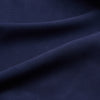 View 4 of product A man stands against a beige backdrop, wearing the Turnbull & Asser Navy Holiday Fit Silk Phillips Shirt with Revere Collar and dark pinstripe pants. He gazes downwards with a relaxed expression, embodying effortless summer style.