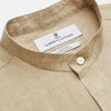 View 4 of product A man with a bald head and trimmed beard wears the Turnbull & Asser Beige Weekend Fit Linen Blake Shirt with stand collar and 1-button cuffs, standing calmly against a matching beige background.