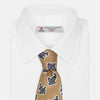 View 4 of product The Turnbull & Asser Toffee Paisley Floral Cotton Silk Blend Tie features a rolled-up design with dark blue and white paisley motifs on a tan background.