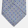 View 3 of product A Turnbull & Asser Blue and Yellow Geometric Silk Jacquard Tie is shown rolled up on a plain light background.
